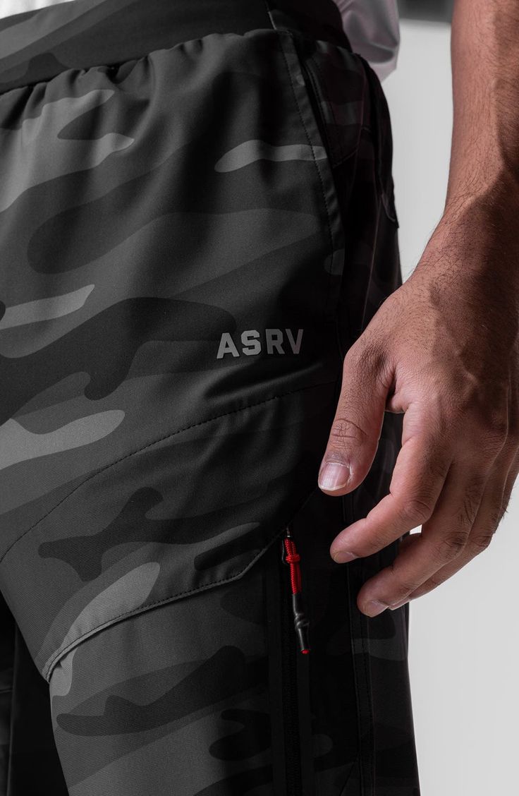 a close up of a person's hand on the waist of a camo - print shorts