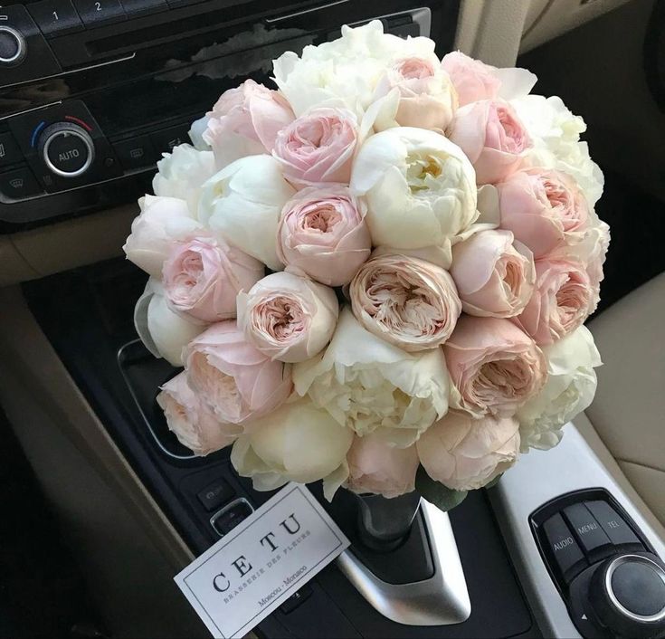 a bouquet of pink and white flowers sitting in the center of a car dash board