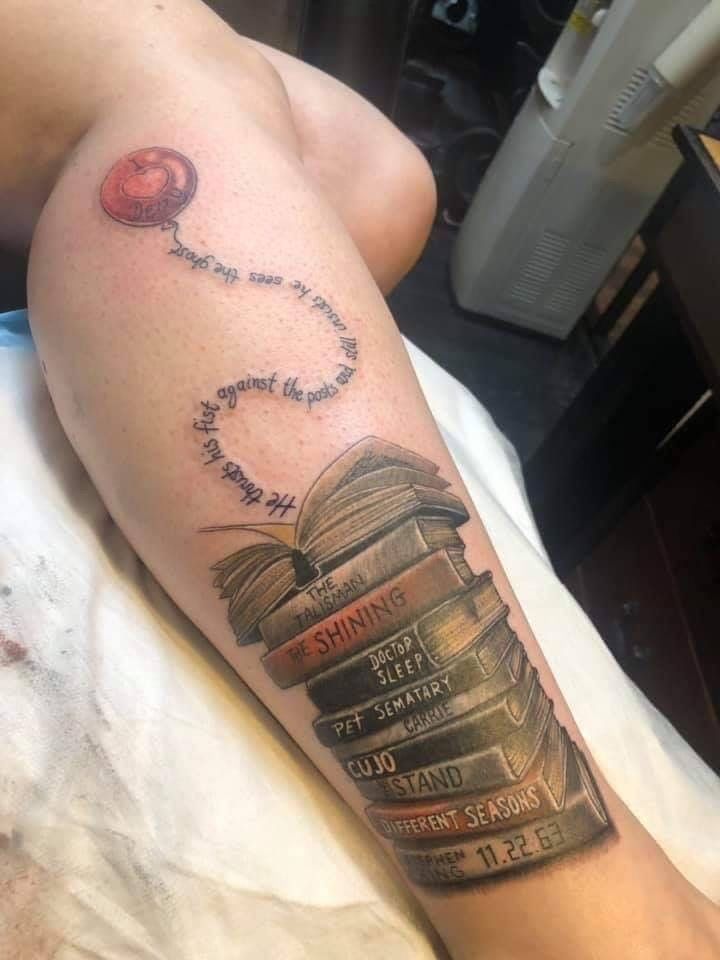 a person with a tattoo on their arm that has books stacked up in the shape of a heart