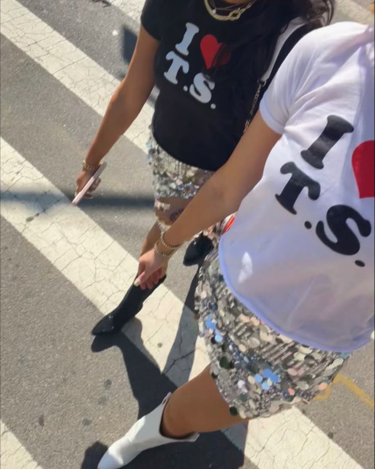 two people walking down the street with one person wearing a t - shirt that says i love you