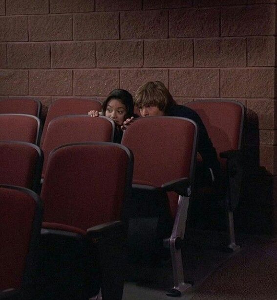 two people sitting on red seats next to each other