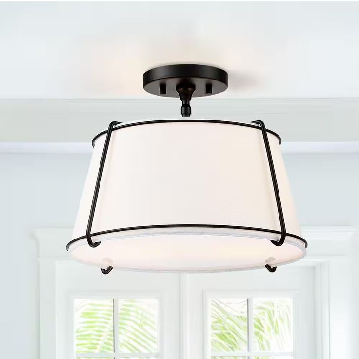 a light fixture hanging from the ceiling in a room with white walls and window frames