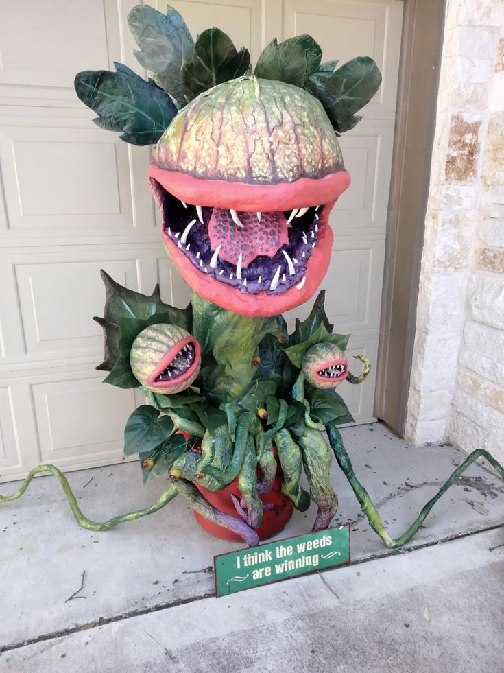 a fake dragon planter sitting in front of a garage door with a sign that says i think the words are winning