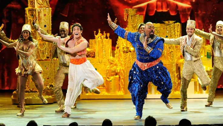 a group of men and women on stage with their arms in the air while dancing