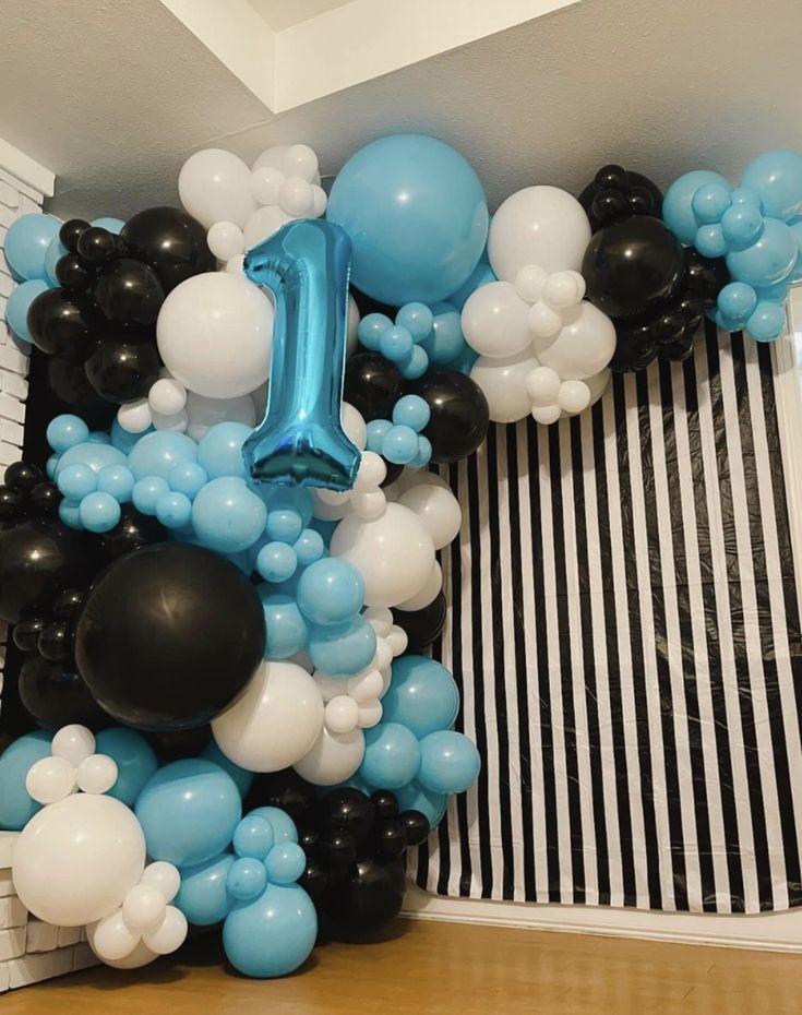 the balloon arch is decorated with black, white and blue balloons