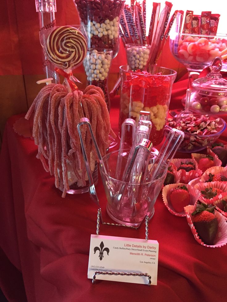 a table topped with lots of candy and candies on top of red cloth covered tables