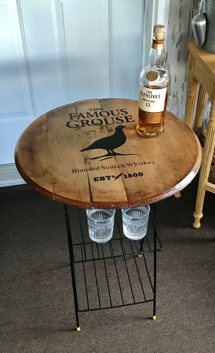 a bottle of liquor sitting on top of a wooden table next to two empty glasses