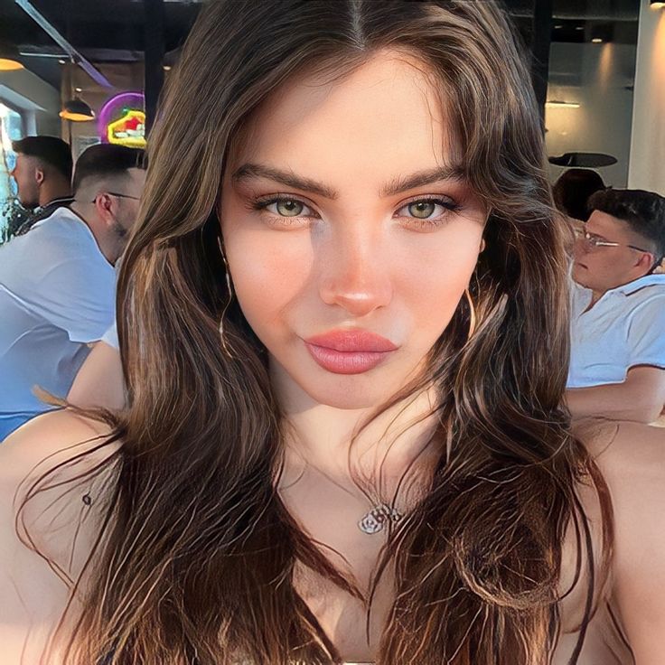 a woman with long brown hair wearing a white dress and posing for the camera at a restaurant