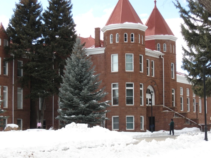 a large red brick building with snow on the ground and trees in front of it