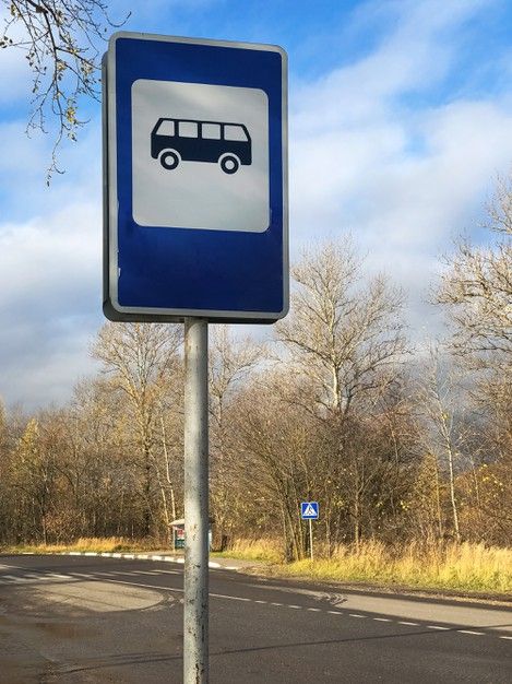 a blue and white street sign sitting on the side of a road next to trees