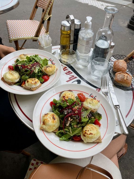 two white plates with food on them sitting next to each other at an outdoor table