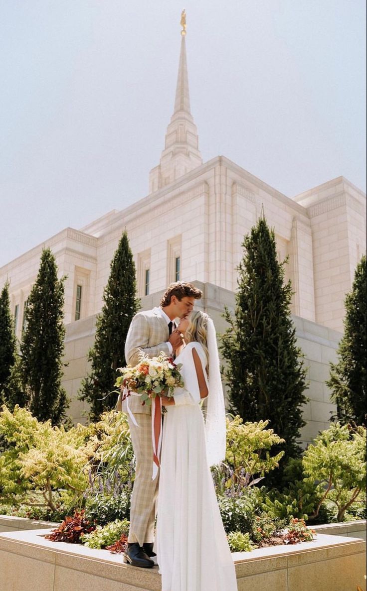 a bride and groom kissing in front of the mormon temple