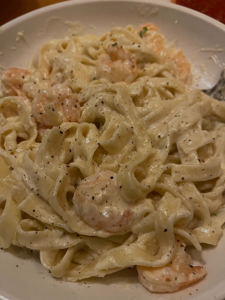 a white plate topped with pasta and shrimp