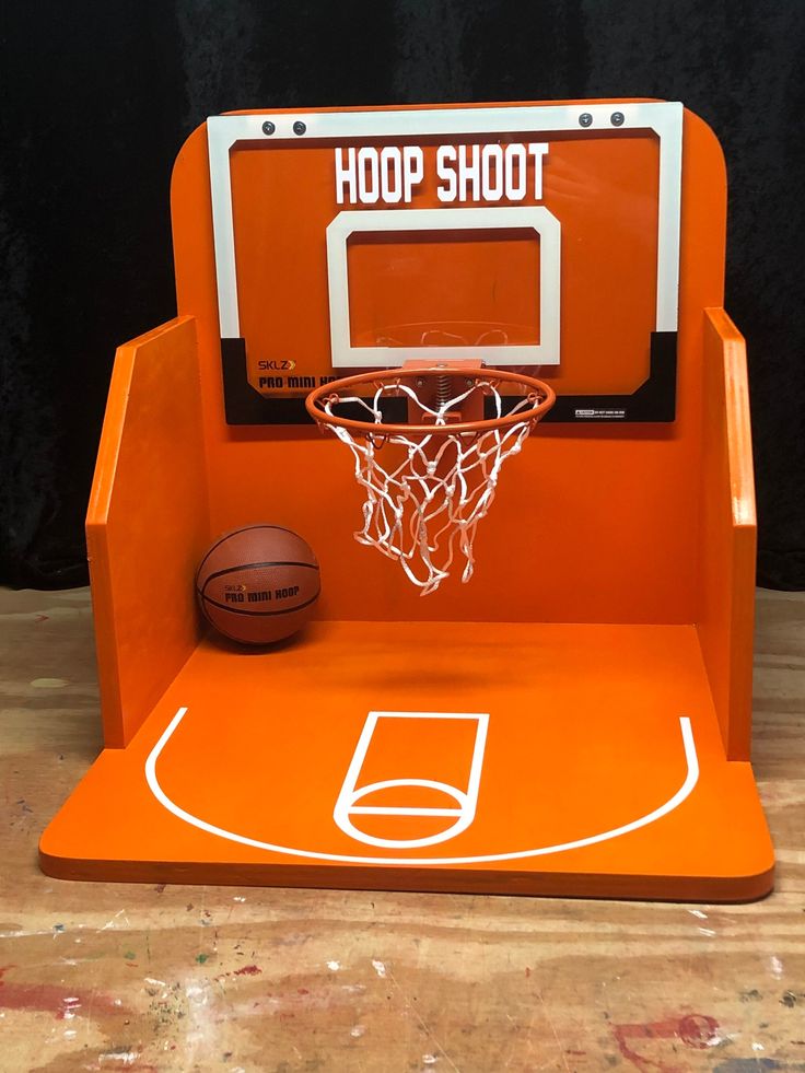 an orange basketball stand with a hoop in it and a basketball on the floor next to it