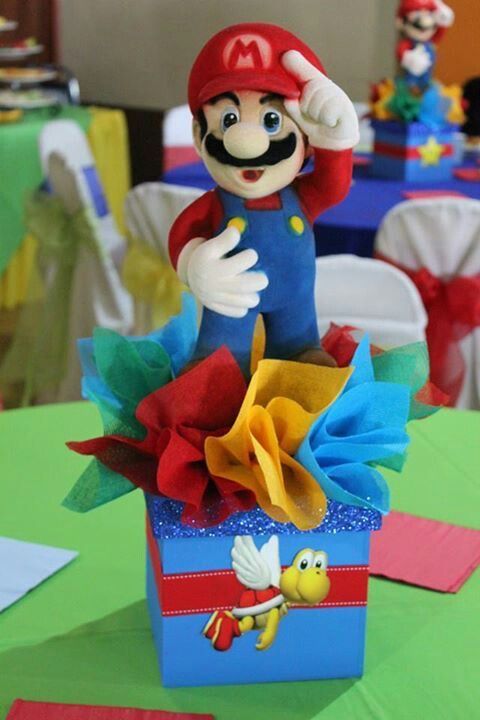 a nintendo mario birthday cake on top of a blue box with red bow and yellow ribbon