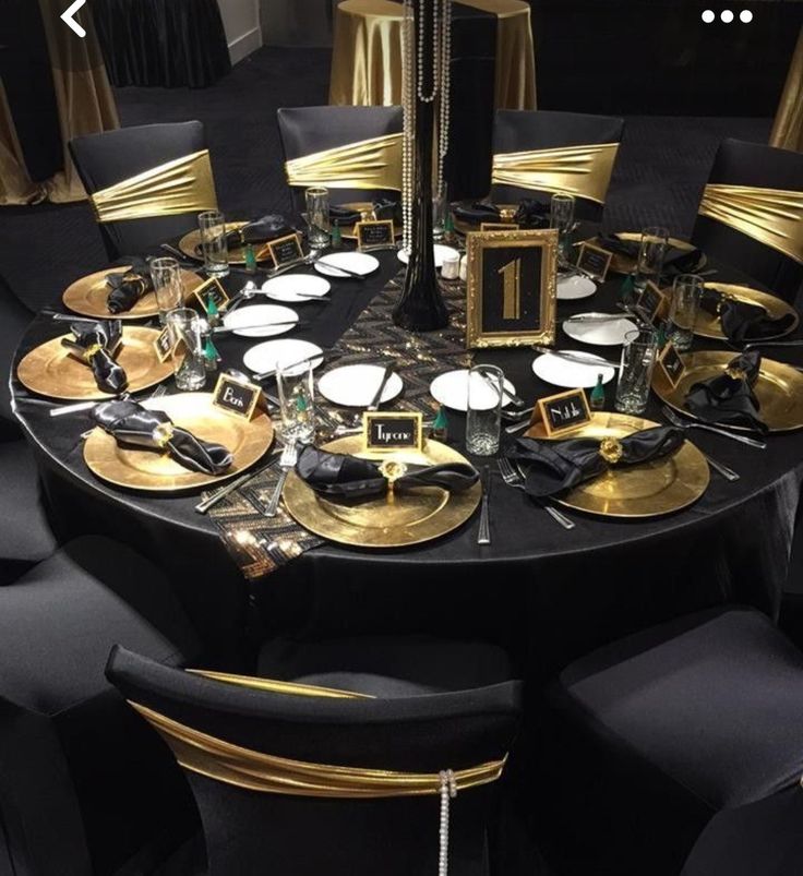 a round table with black and gold plates, silverware and napkins on it