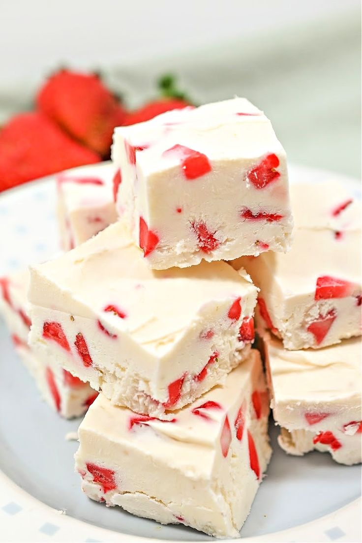 strawberry shortbread fudges are stacked on a plate with strawberries in the background