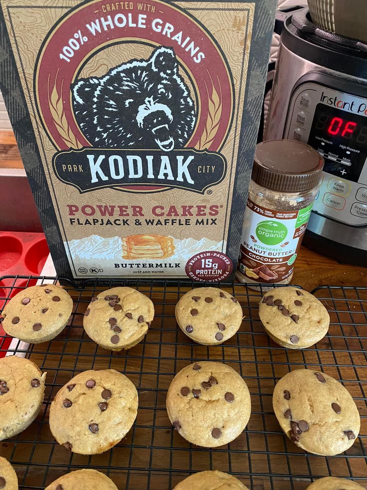 chocolate chip cookies cooling on a rack next to a box of kodiak powdered sugar