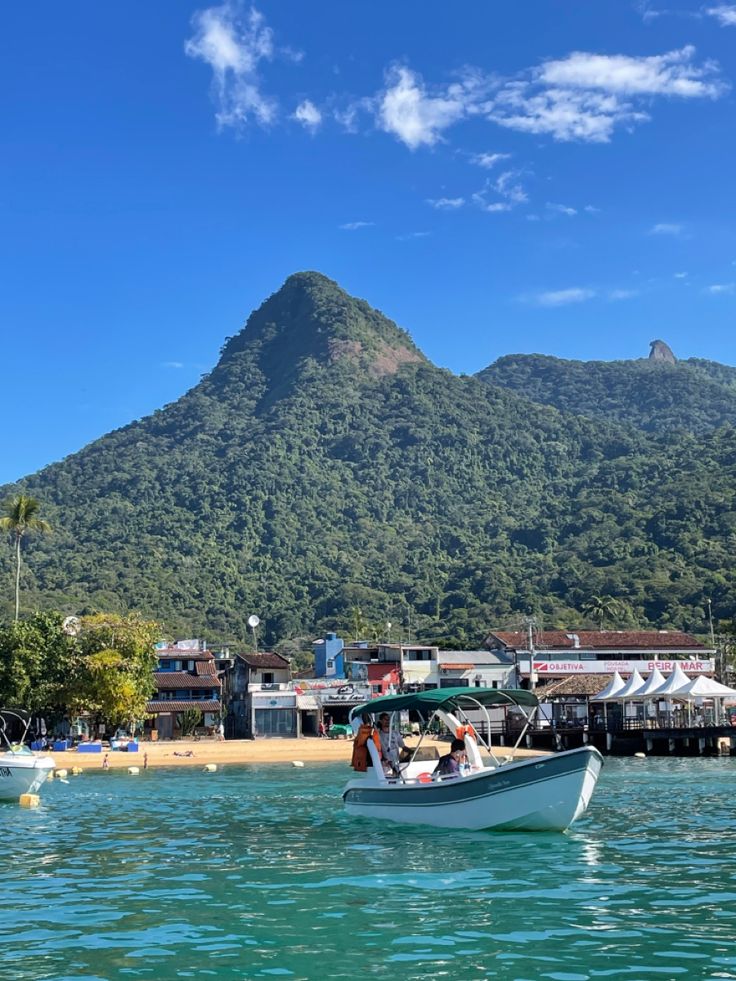 a small boat in the water with a mountain in the background