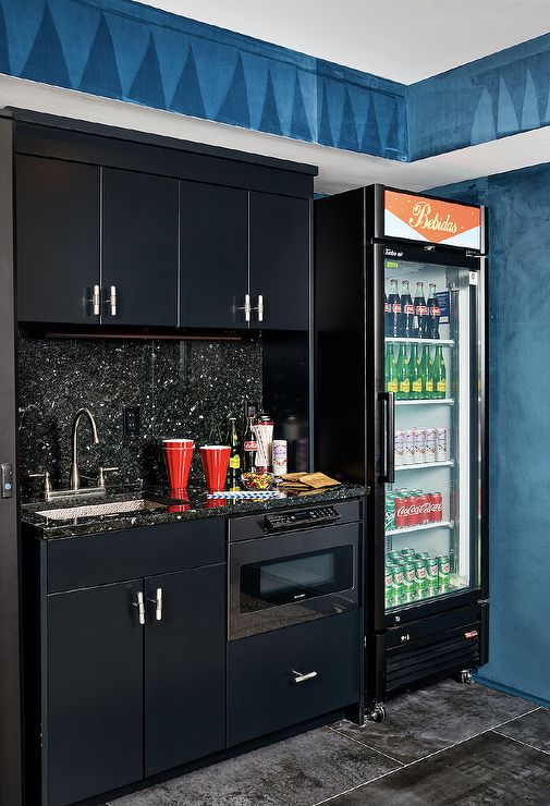 the refrigerator is full of beverages and drinks in it's black cabinets, along with other appliances