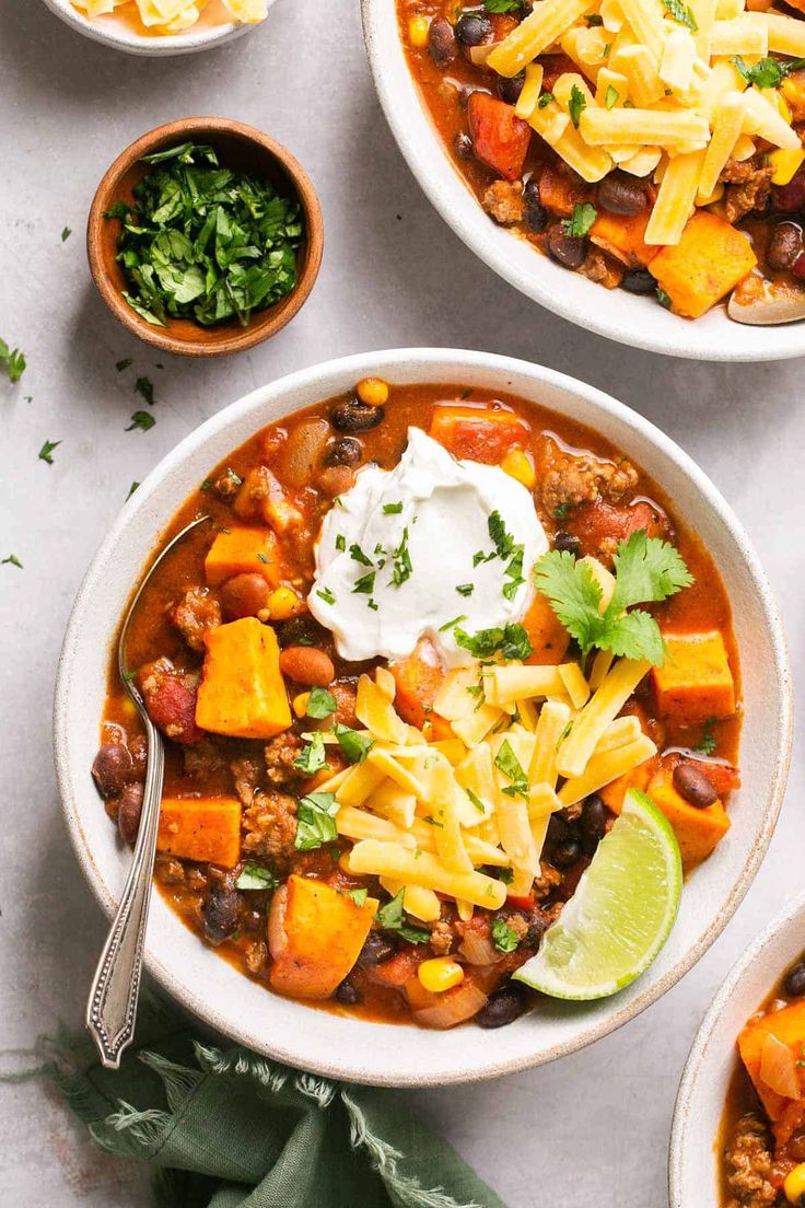 two bowls filled with chili, cheese and tortilla bread on top of a table