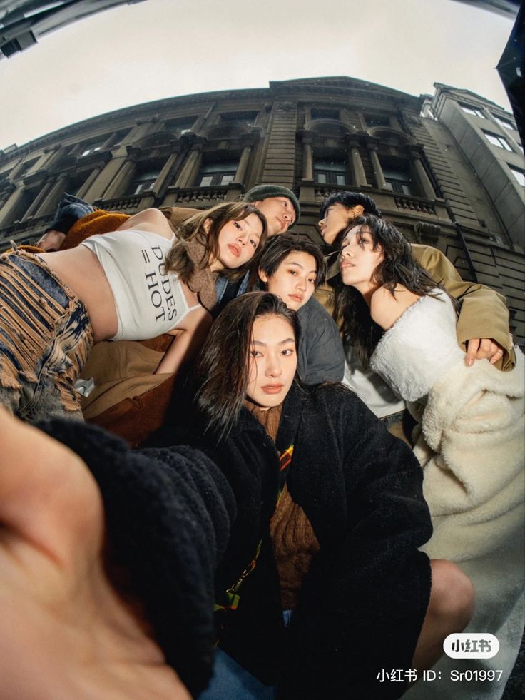 a group of young women taking a selfie in front of a tall building on a sunny day