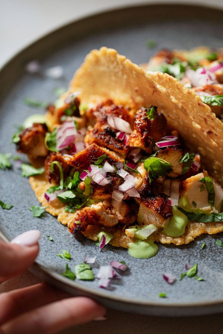 two tacos are on a plate with onions and cilantro sprouts