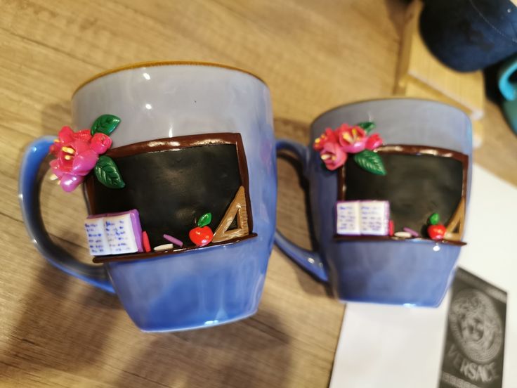 two coffee mugs decorated with magnets and flowers