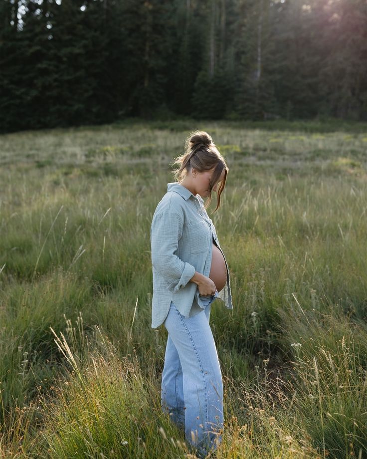 a pregnant woman standing in the middle of a field