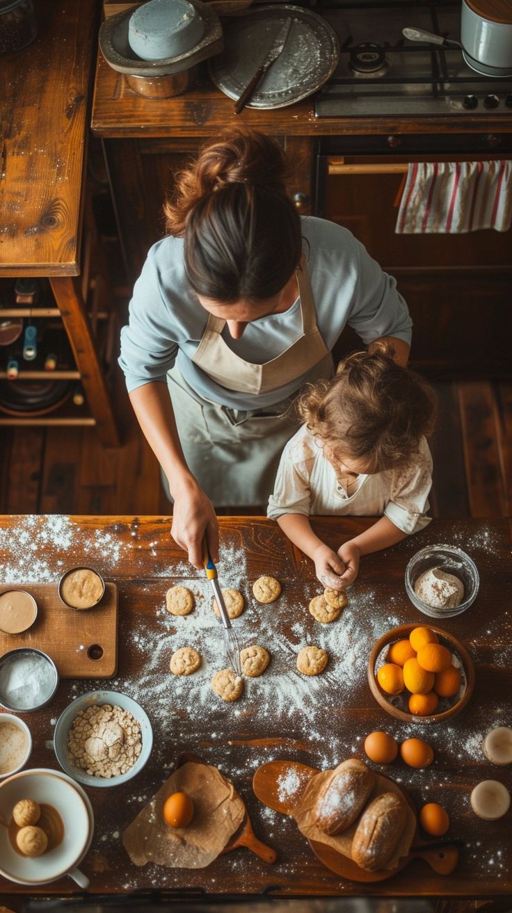 an overhead view of a woman and child making cookies on a table with oranges