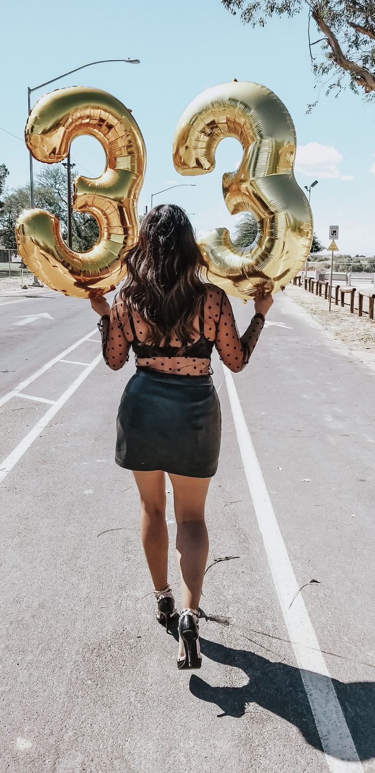 a woman is walking down the street with balloons in her hands that read 3 / 3