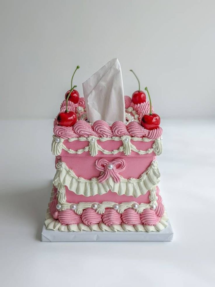 a pink and white cake with cherries on top