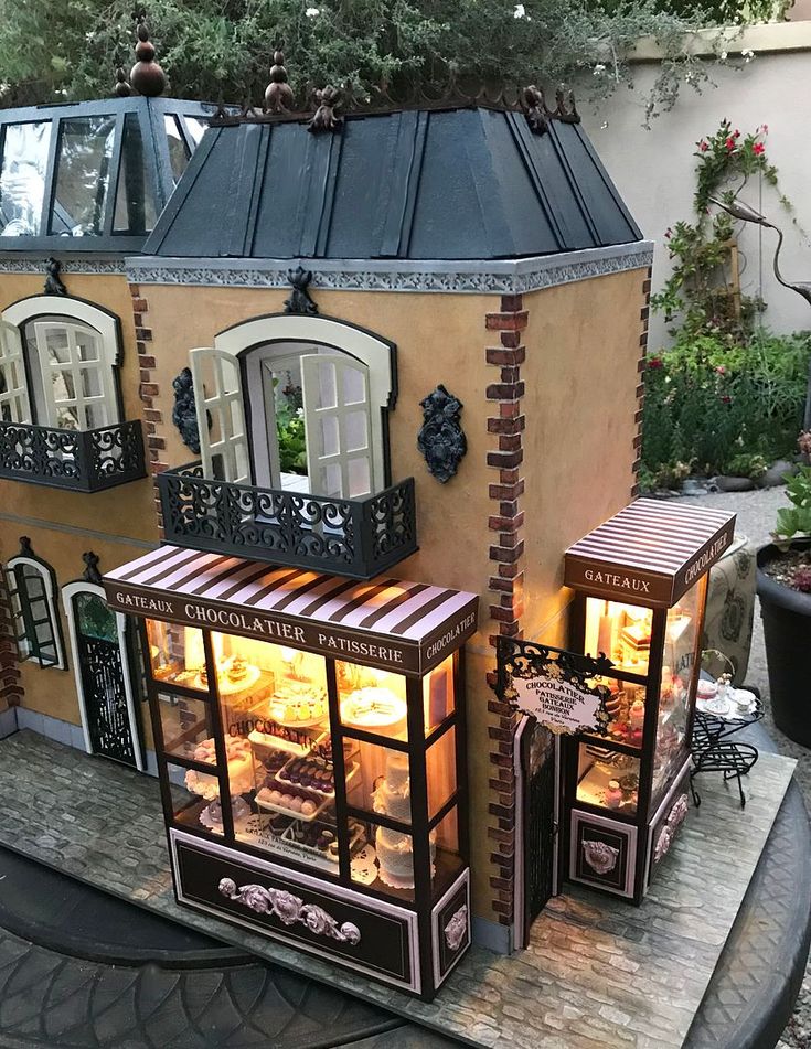 a doll house is shown with its lights on and windows open in front of it