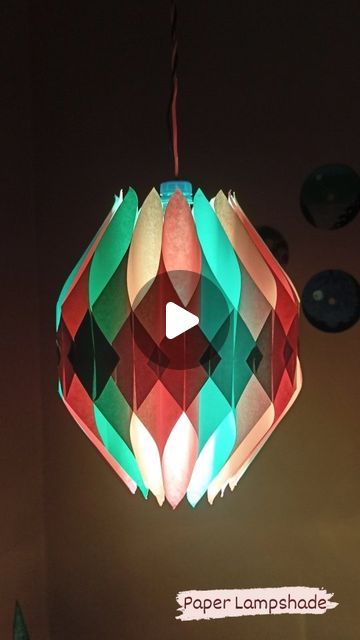 a multicolored paper lamp shade hanging from a ceiling in a room with other lights