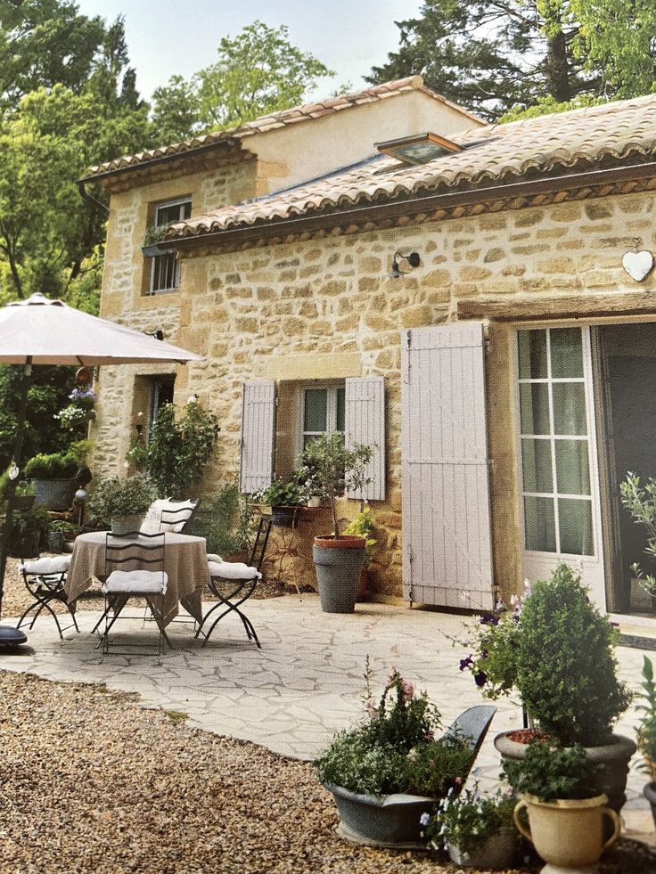 an outdoor patio with tables and chairs next to a stone building that has shutters on it