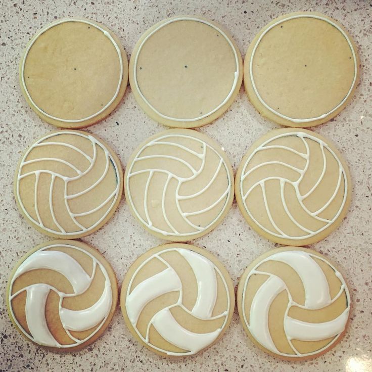 six cookies decorated like volleyballs sitting on a counter top with icing around them