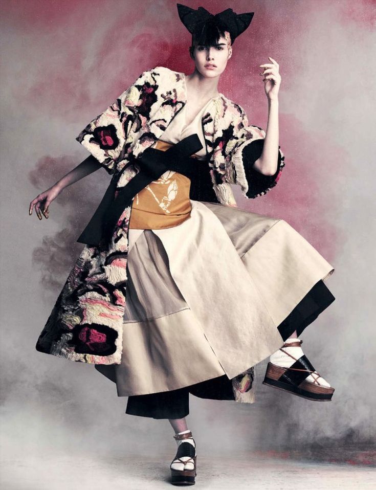 a woman in a kimono and hat poses for the camera with her hand on her hip