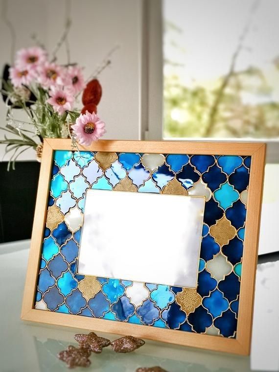 a blue and white mosaic tile frame with flowers in the background on a glass table