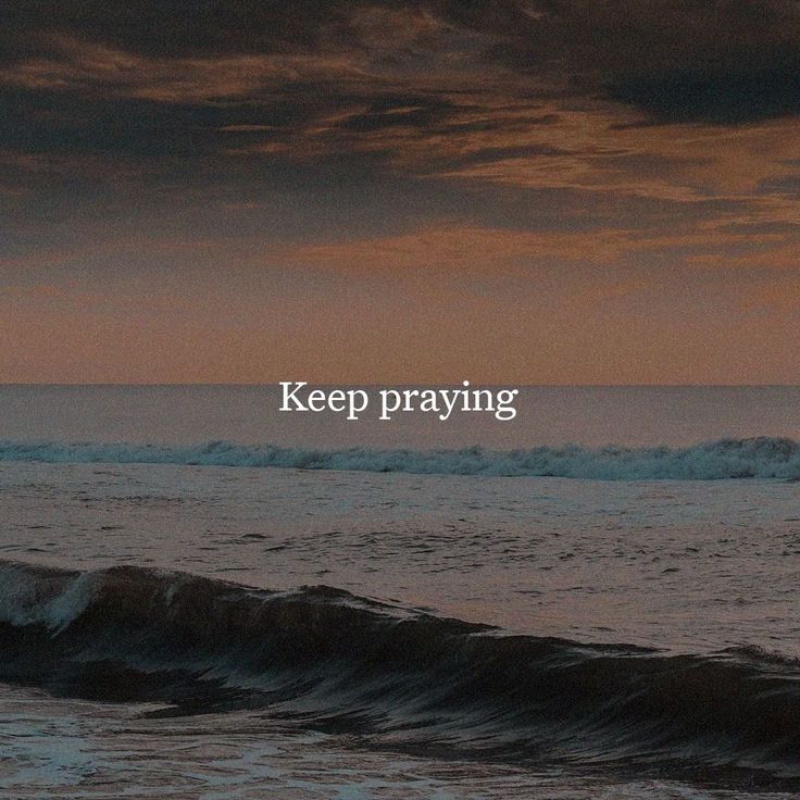 the words keep praying are written in white on top of an ocean wave at sunset