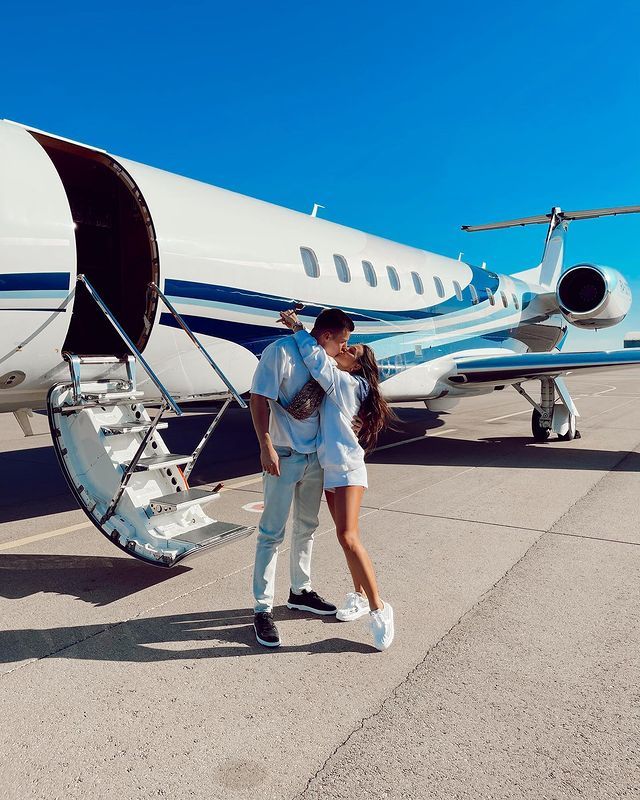 a man and woman standing in front of an airplane