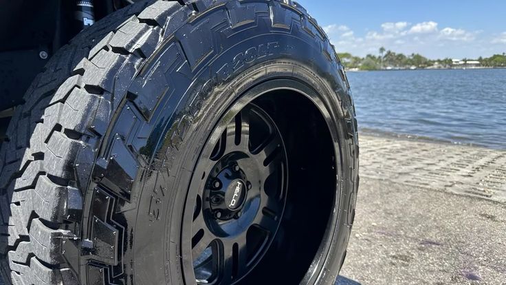 the front tire of a truck parked by the water