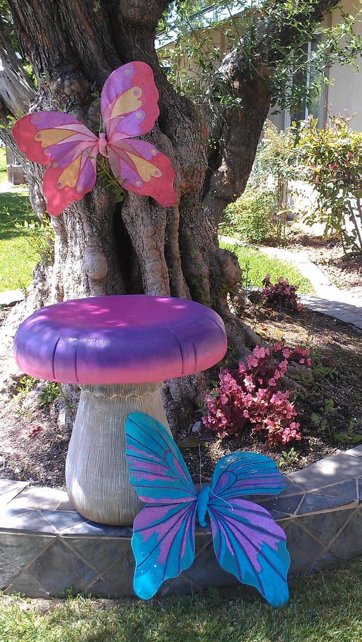 an inflatable butterfly sitting on top of a birdbath next to a tree