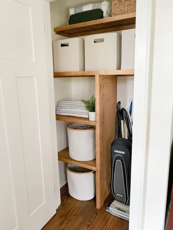 an open closet with several bins and baskets on the shelves, along with other items