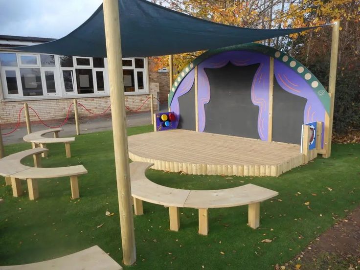 an outdoor play area with benches and a stage