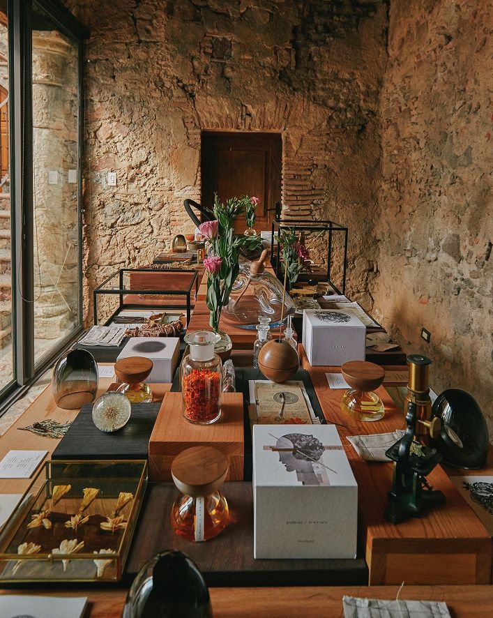 a long table with many items on it in front of a glass window and stone wall