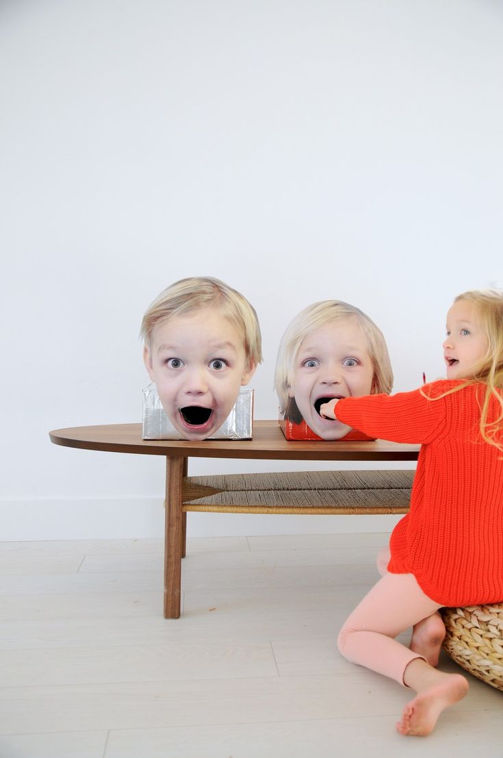 two young children sitting on the floor in front of a table with their mouths open