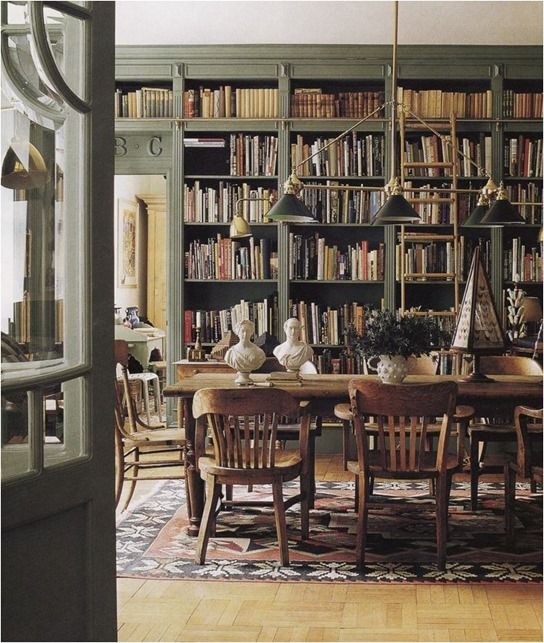 a dining room table and chairs in front of a bookshelf filled with books