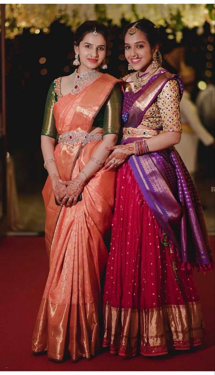 two women standing next to each other on a red and gold floored area with lights in the background