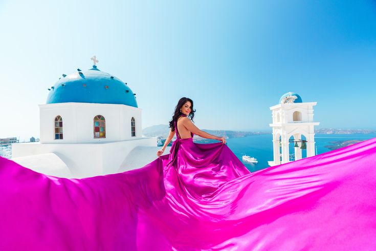 a woman in a pink dress standing on the roof of a building with a blue dome