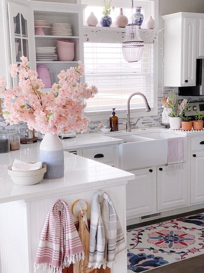 a kitchen with white cabinets and pink flowers